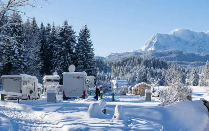 Winterszenerie mit verschneiten Bergen und Wohnmobilen